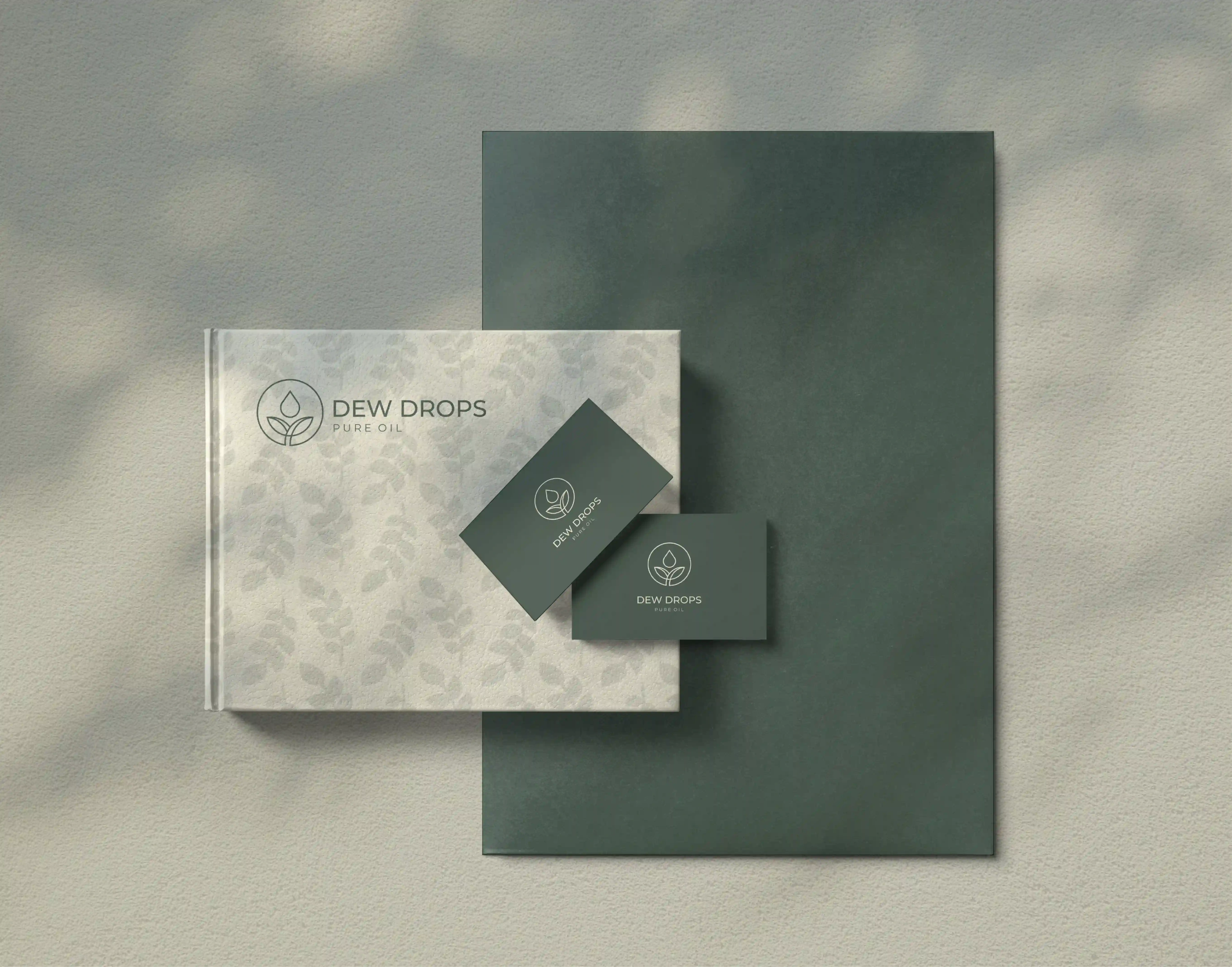 Dew Drops notebook and business cards with leaf pattern beside a green folder