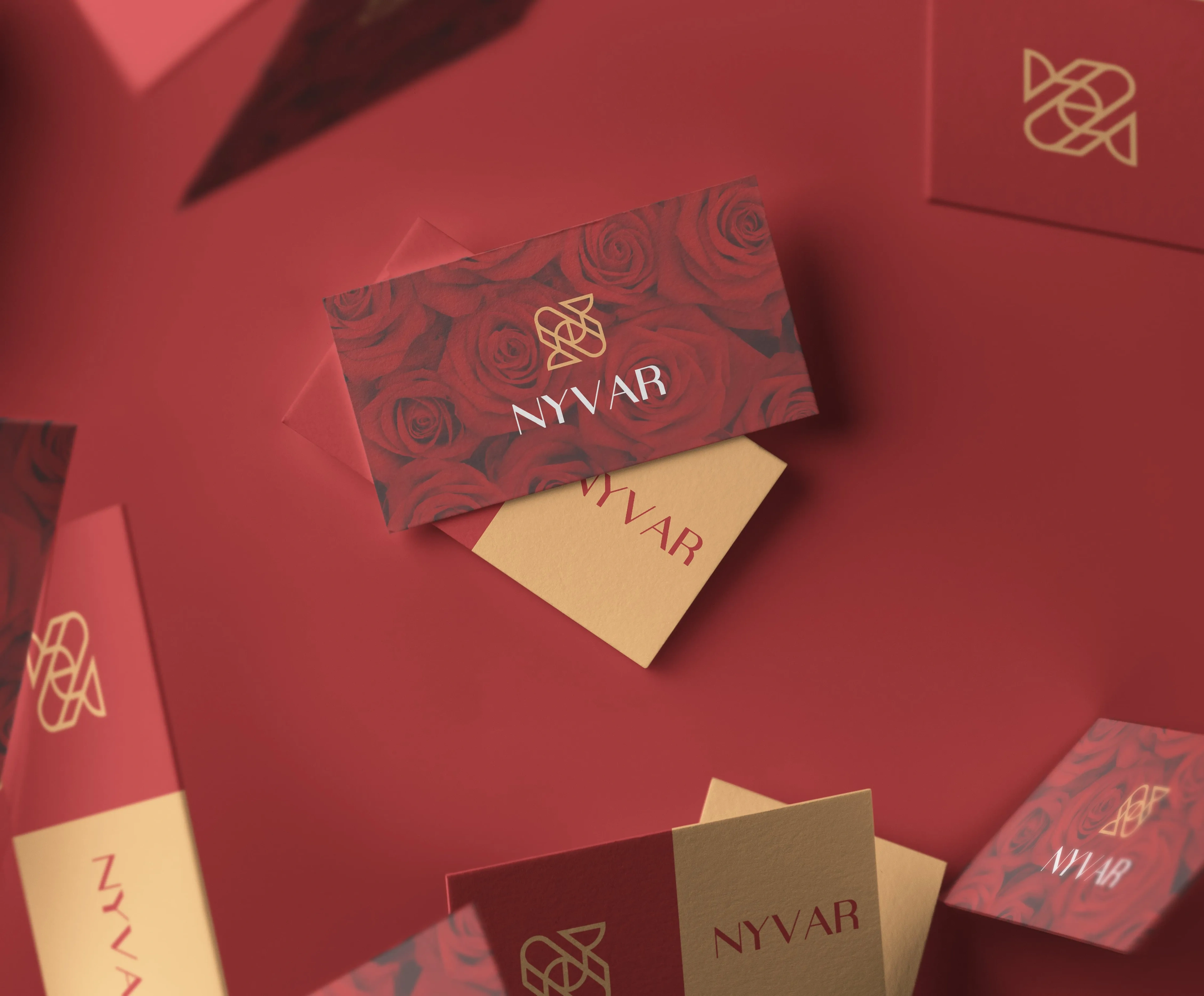 Nyvar business cards in red and gold on a red rose-print surface