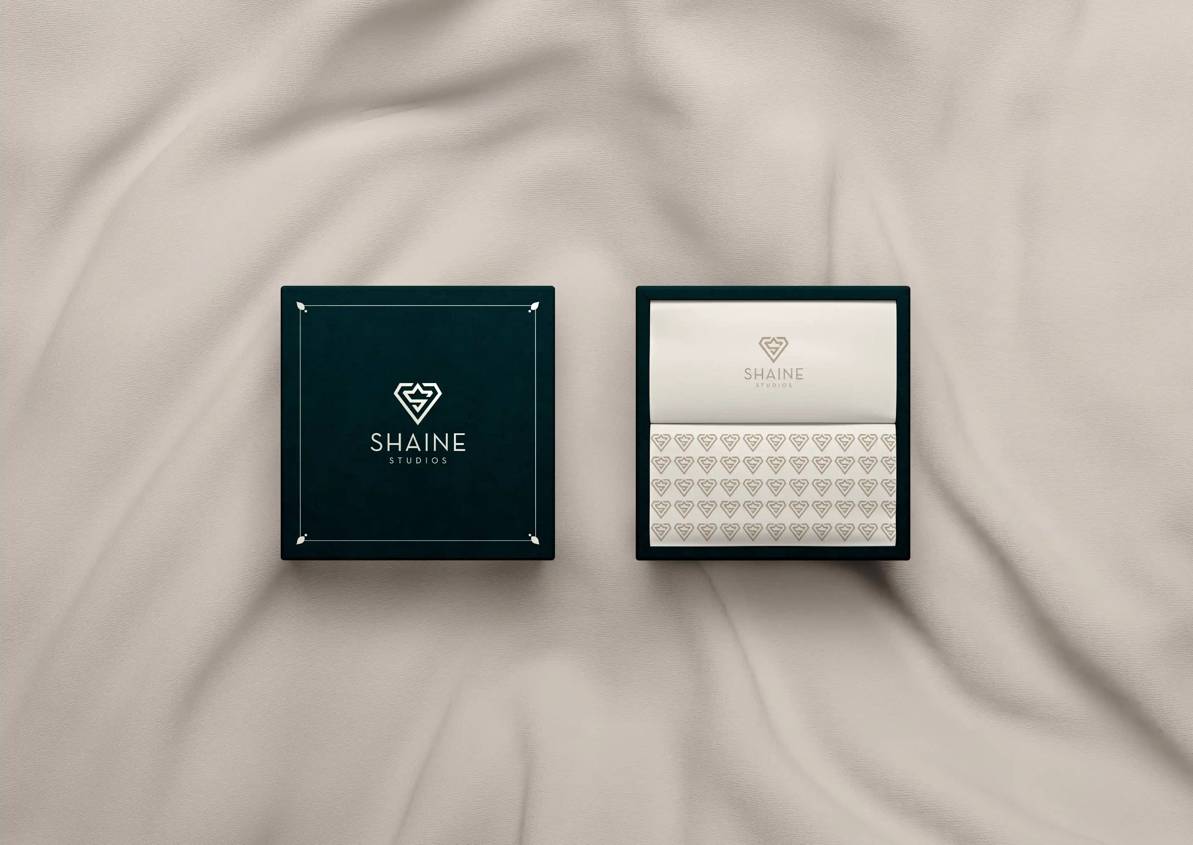 Two Shaine Studios gift boxes on cream silk, one open